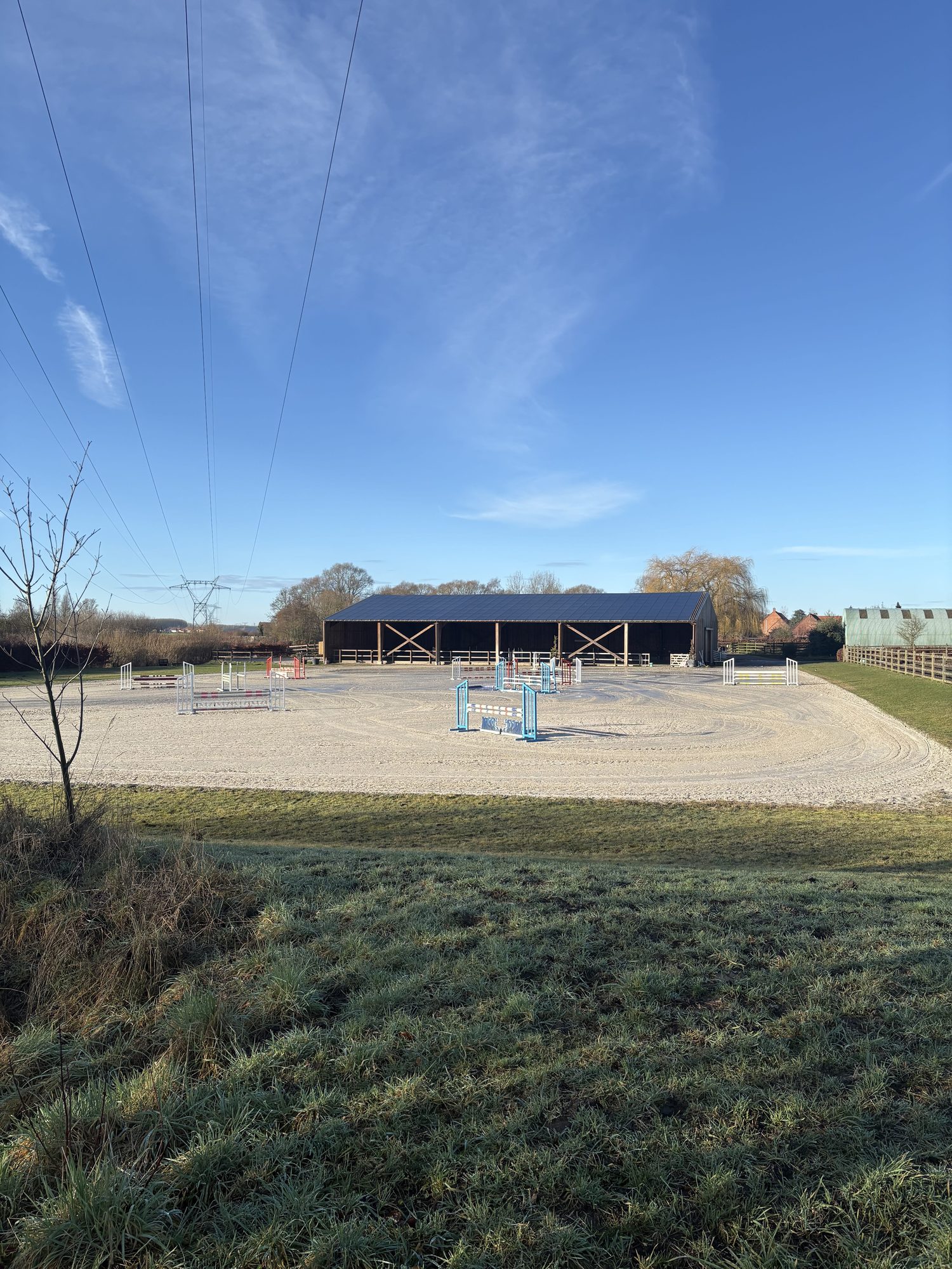 Vue extérieure du manège et de la carrière depuis les prés en hiver.